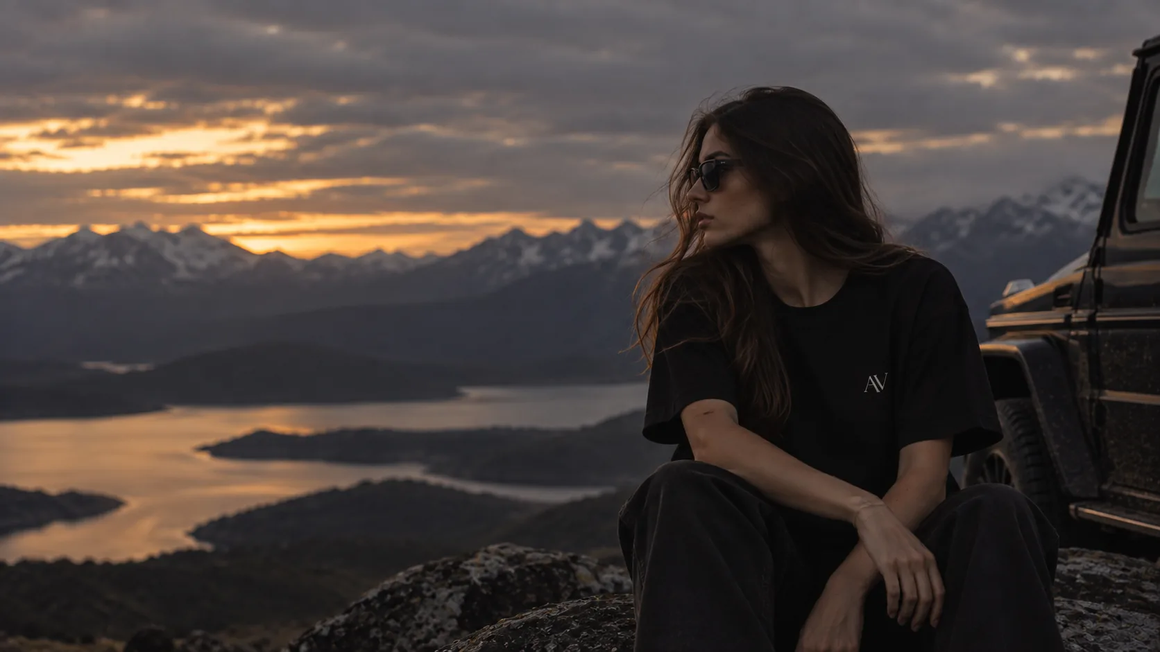 Modelo con la Perspective T-Shirt negra frente al paisaje al atardecer